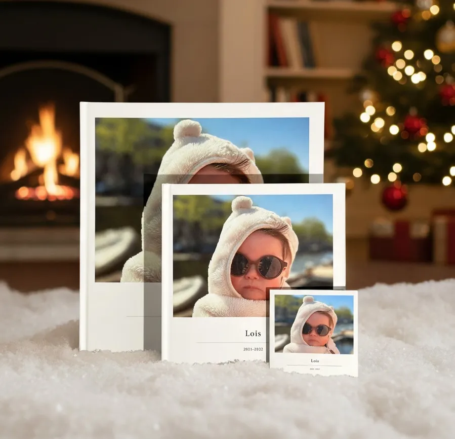 Een opengeslagen lay-flat kerstfotoboek op een salontafel naast een mok en dennentakken.