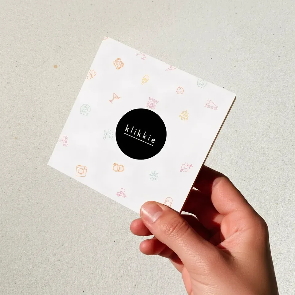 Een klikkie pocket fotoboek cadeau ligt open op een keukentafel naast een kop koffie
