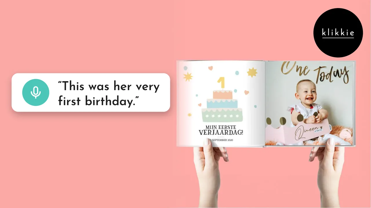 Hands holding an open klikkie My First Year photo book with a first birthday page, with the words “This was her very first birthday.”